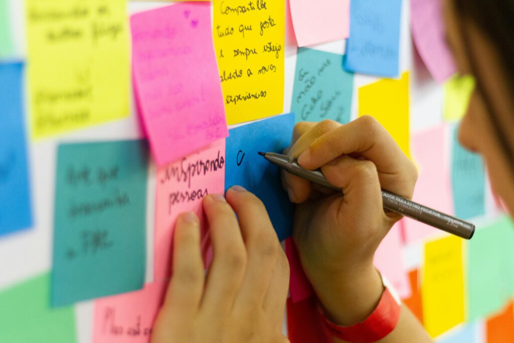 Brainstormsessie over online marketing oplossingen, waarbij een persoon ideeën noteert op gekleurde sticky notes op een bord vol strategieën en concepten.